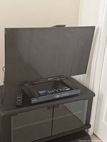 Sony 32-inch TV on stand with Blu-ray player and remote visible