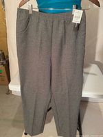 Full view of grey straight-leg pants hanging, tags visible