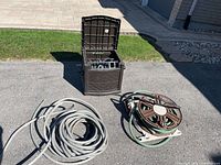 overview of storage box, coiled grey hose, hose reel with green hose