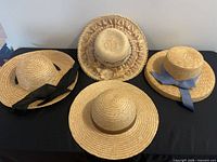 Group shot of four straw hats showing ribbon colors and styles