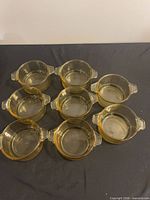 Top view of seven of the eight amber glass ramekins with handles