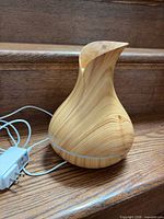 Asakuki diffuser with power adapter coiled beside unit on wooden stair