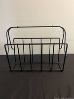 Front view of black metal holder showing five slots
