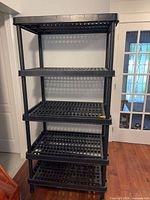 Full front view of five-tier black plastic shelving unit