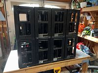 Eight black plastic wine crates stacked on workbench