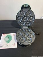 Dash donut maker open showing two non-stick 7-cavity plates and manual