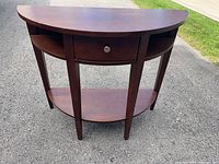 Front view of half-moon console table showing drawer, side cubbies, and lower shelf