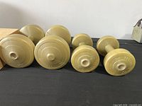 All four beige plastic dumbbells on black surface