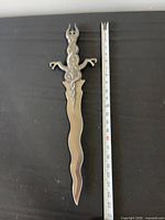 Full view of dagger alongside tape for scale