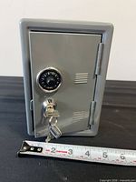front view safe door closed, dial and keys visible, tape for width