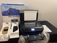 Printer on table with lid open, box, foam inserts, manual visible
