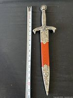 Full dagger in sheath beside tape measure showing 17 inch length