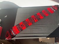 Full view of red and black UNB Varsity Reds scarf laid flat showing length and pattern