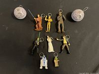 Group shot of eight Star Wars character keychain figurines and two Death Star capsules on black surface