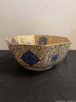 Exterior side view of hexagonal porcelain bowl showing blue medallions and gilt detailing