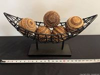 Front view of stand holding five balls with tape for scale