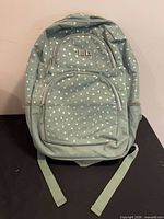 Front view of mint green backpack with heart pattern showing front pockets and logo