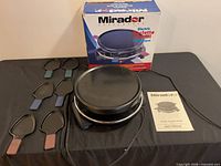 Overall lot showing raclette appliance, six pans, cable, manual, and box
