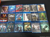Full grid of 18 Blu-ray cases on black surface