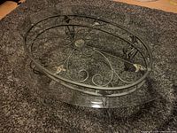 Angled view of oval glass coffee table showcasing metal base and glass top