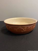 Side view showing brown exterior with embossed floral vine pattern and cream interior