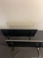 Two black wall shelves viewed from top showing attached brackets