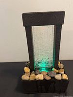 Front view showing glass panel, frame, pebbles, green LED