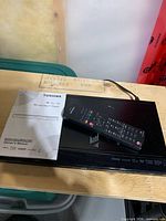 Top view showing Blu-ray player, remote, and manual