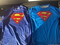 Both Superman shirts side by side to show colors and logos