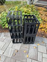 Stack of eight black plastic WEIN bottle crates outdoors