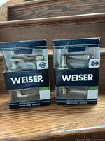 Front view of two boxed Weiser satin nickel passage door knobs