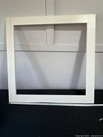 Full view of white wood picture frame front against wall
