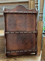 Front of wooden spoon rack showing three rows of slots for 18 spoons
