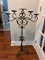 Full view of wrought iron 5-arm floor candelabra showing scrollwork and tripod base