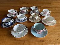 All ten teacup and saucer pairs laid out on wood floor