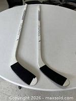 Two HLPA Junior Flex hockey sticks on a table, full view