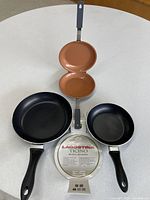 Top view showing both Lagostina skillets and opened omelette pan to display interiors