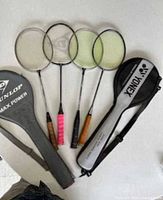 Four badminton racquets with two covers displayed on table