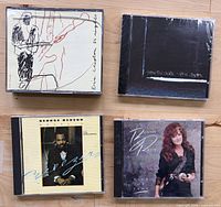 Front view of four CD jewel cases showing album covers