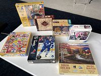 Seven puzzle boxes on a table showing fronts and piece counts