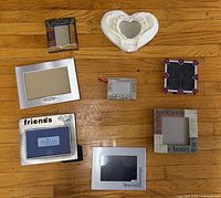 All eight photo frames laid out on floor, various sizes and styles visible