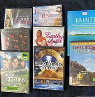 Group shot of seven visible DVD cases including Aurora Borealis, Heaven Is for Real, Tahiti, Stone of Destiny, Earth Angel, Unexplained Mysteries 2-disc set, Travel the World by Train