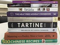 Stack of nine cookbooks showing titles on spines