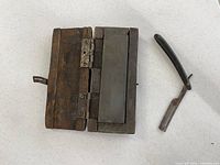 Whetstone in wood case alongside folded straight razor