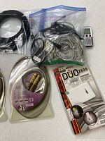 Group view showing Duo 2600 power bank package, two sealed digital coax cables, assorted cables in bag, Olympus recorder, Sharp radio