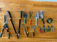 Overview showing hedge shears, loppers, cultivators, trowel, wire spool and pruners