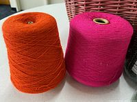 Orange and pink yarn cones side by side on tabletop