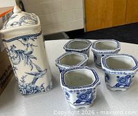 Canister with lid and five small planters on table