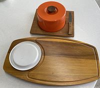 All main pieces laid out: large oval board with ceramic insert, square board, orange dome on square board, knife