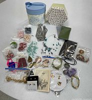 Full lot overview showing both decorative boxes, assorted jewelry bags, loose items and eyeglass sleeves